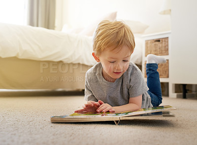 Buy stock photo Shot of a young boy reading a book at home