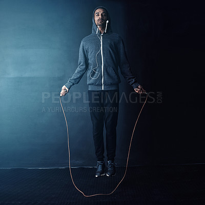 Buy stock photo Studio shot of a young man skipping against a dark background