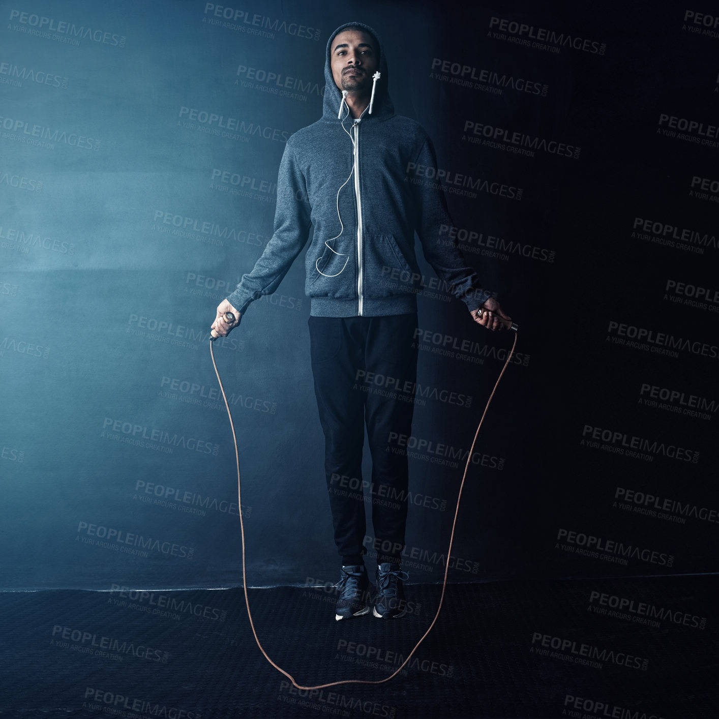 Buy stock photo Studio shot of a young man skipping against a dark background