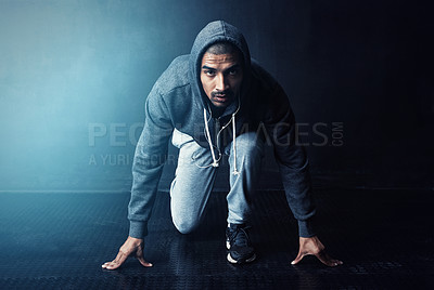 Buy stock photo Studio portrait of a sporty young man getting ready to run against a dark background