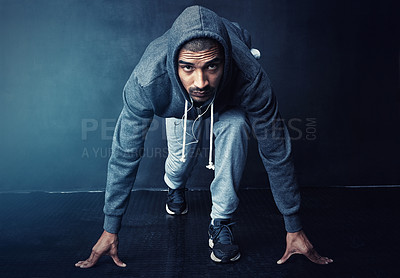 Buy stock photo Studio portrait of a sporty young man getting ready to run against a dark background