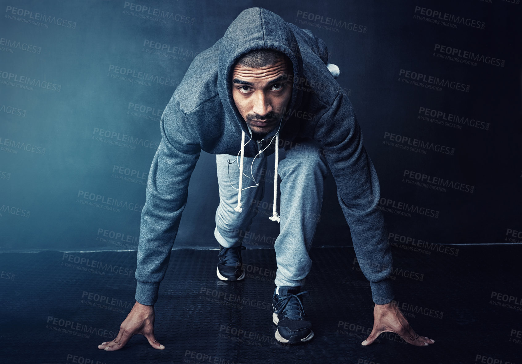 Buy stock photo Studio portrait of a sporty young man getting ready to run against a dark background