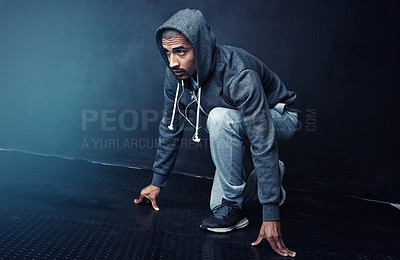 Buy stock photo Studio shot of a sporty young man getting ready to run against a dark background