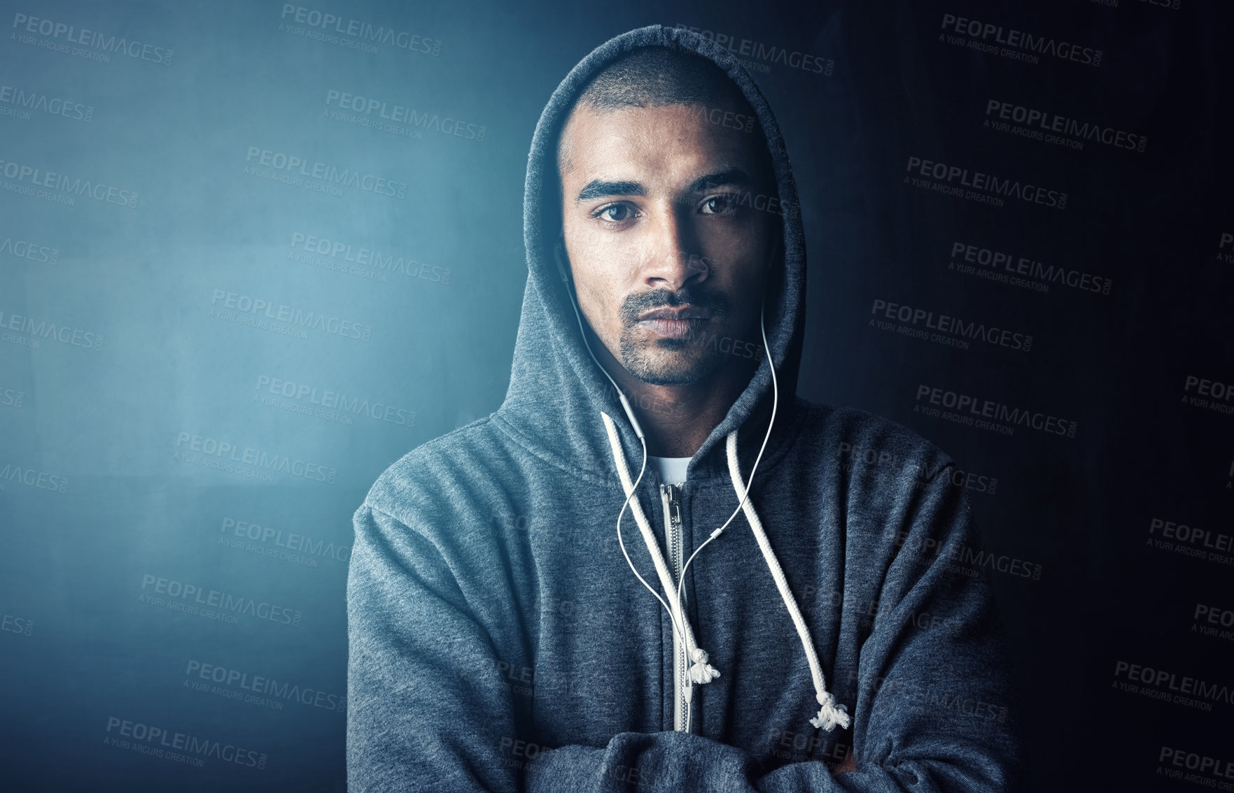 Buy stock photo Man, arms crossed and earphones in studio for workout with portrait, training and hoodie by dark background. Person, audio and streaming music to start exercise, pride and fitness routine in Mexico