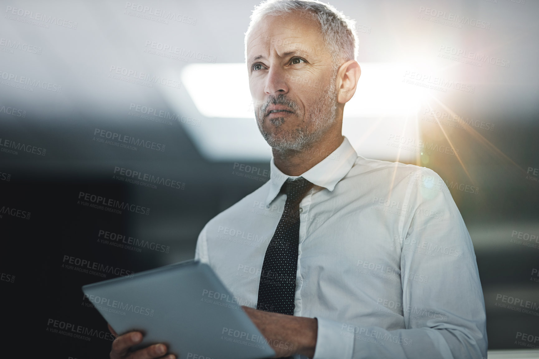 Buy stock photo Shot of a businessman standing in an office using a digital tablet