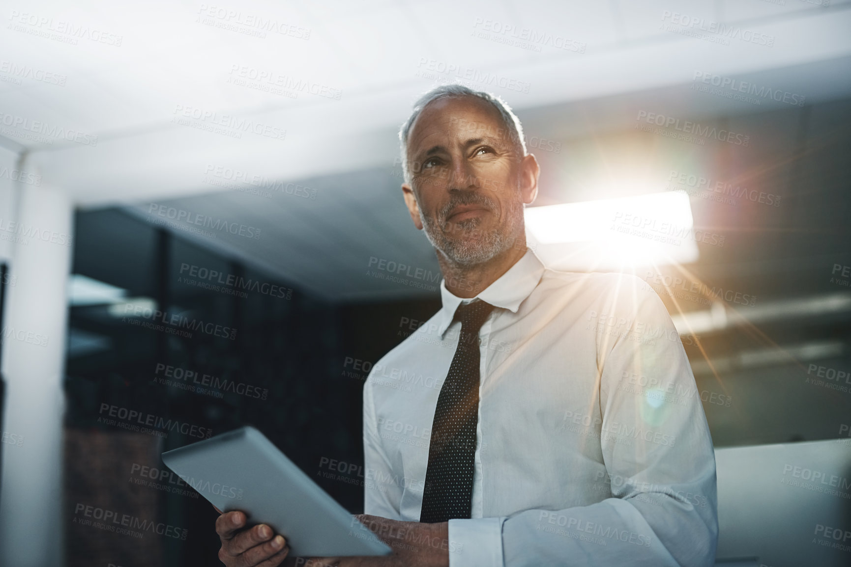 Buy stock photo Shot of a businessman standing in an office using a digital tablet