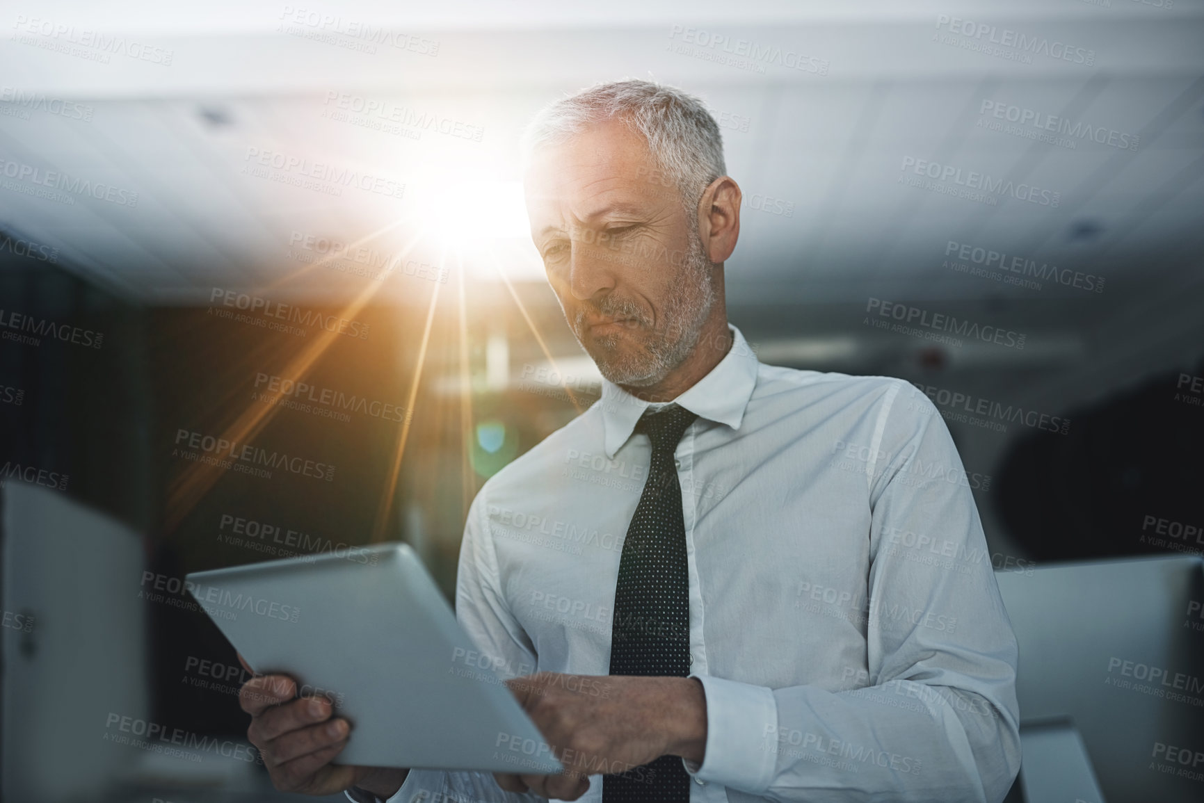 Buy stock photo Shot of a businessman standing in an office using a digital tablet