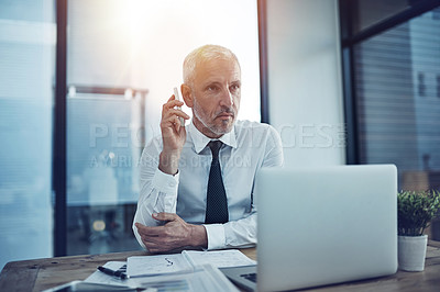 Buy stock photo Shot of a businessman sitting at his desk talking on a cellphone