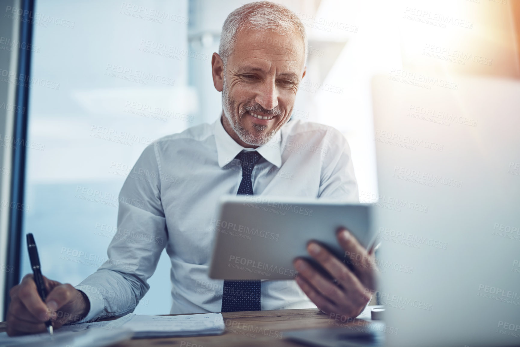 Buy stock photo Shot of a businessman sitting at his desk using a digital tablet