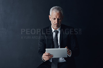 Buy stock photo Business, man and serious on tablet in studio on internet or website, news or stock exchange on black background. Mature person, ceo and browse online for updates on economy, market share and trading