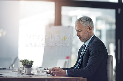 Buy stock photo Shot of a mature businessman sending a text message while sitting in his office