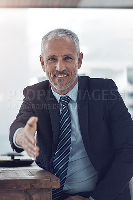 Buy stock photo Portrait of a mature businessman offering you his hand while stting in his office