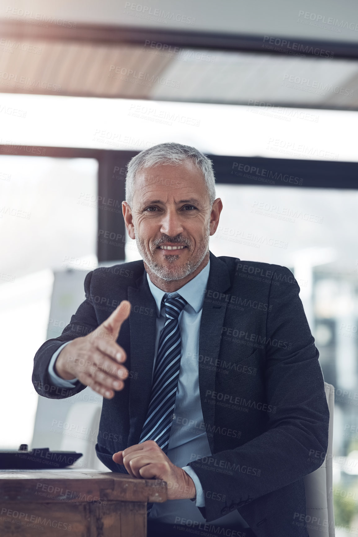 Buy stock photo Portrait of a mature businessman offering you his hand while stting in his office