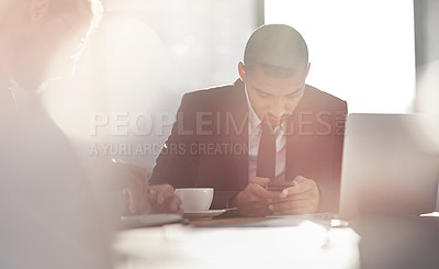 Buy stock photo Shot of a young businessman using his smartphone at work