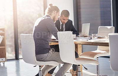 Buy stock photo Shot of two young businessmen working diligently in a modern office