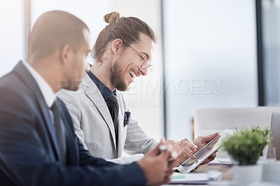 Buy stock photo Shot of two young businessmen using a digital tablet together at work