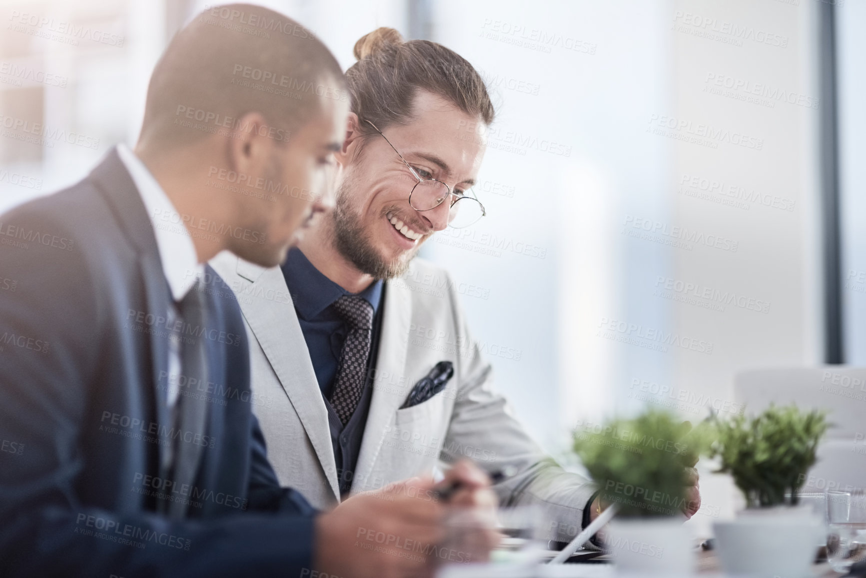 Buy stock photo Shot of two young businessmen using a digital tablet together at work