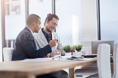 Buy stock photo Shot of two young businessmen using a digital tablet together at work
