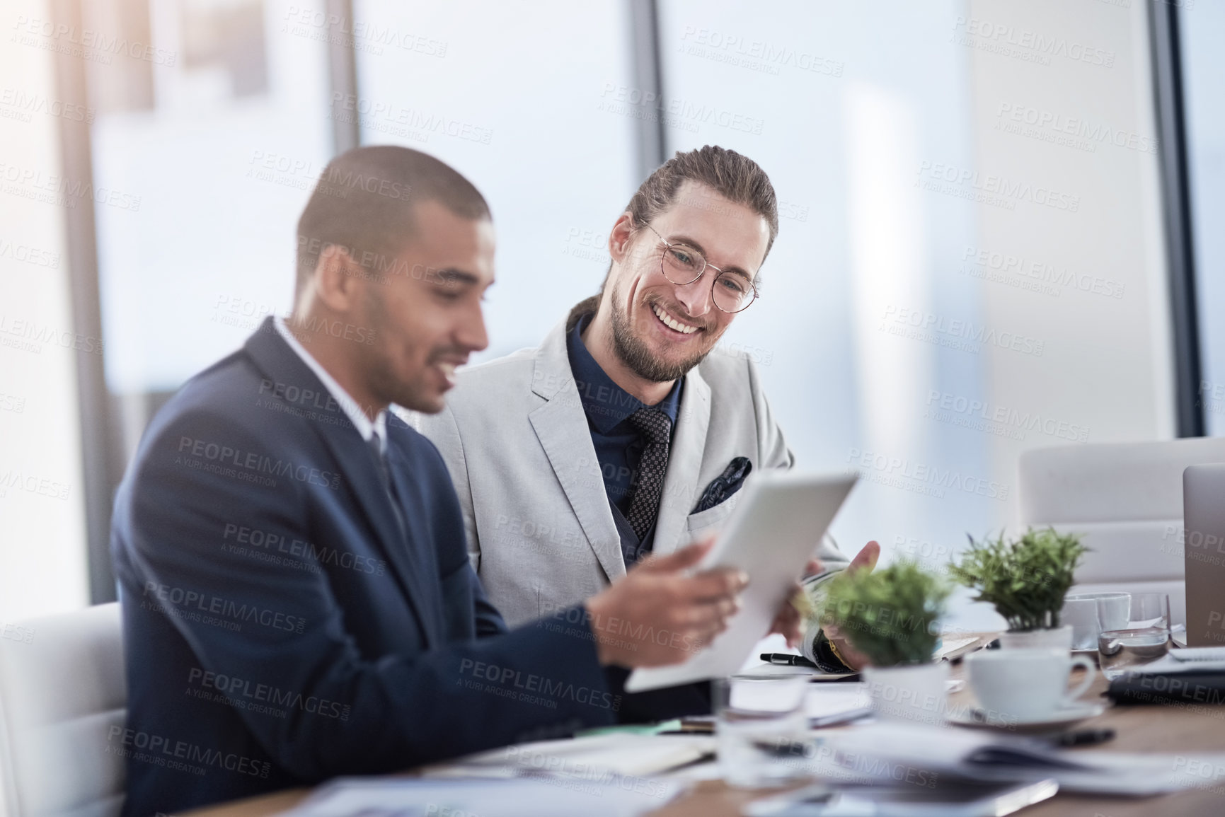 Buy stock photo Shot of two young businessmen using a digital tablet together at work