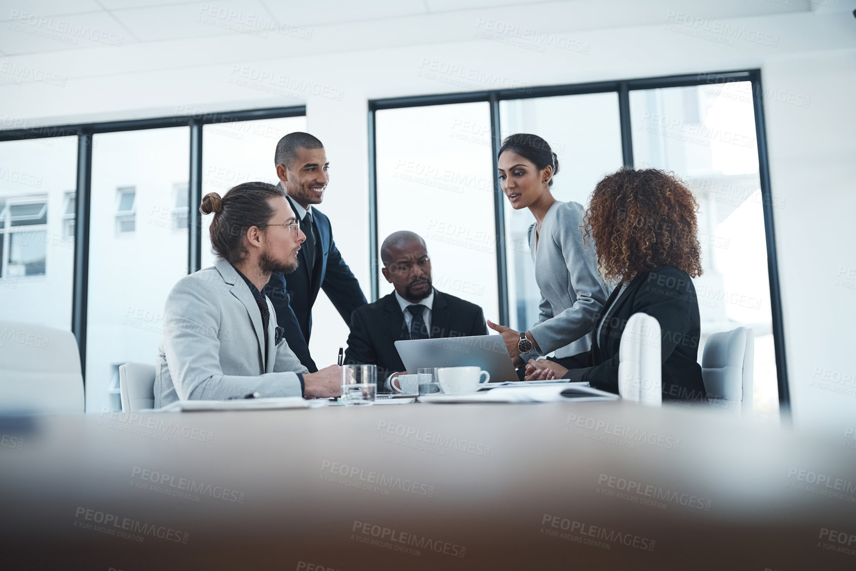 Buy stock photo Shot of a group of businesspeople discussing something on a laptop