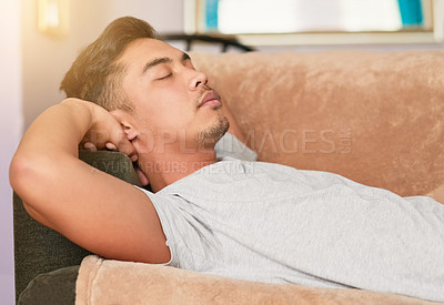 Buy stock photo Shot of a young man sleeping on his couch at home