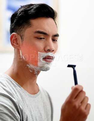 Buy stock photo Shot of a young man at home getting razor burn on his face from shaving with a disposable razor