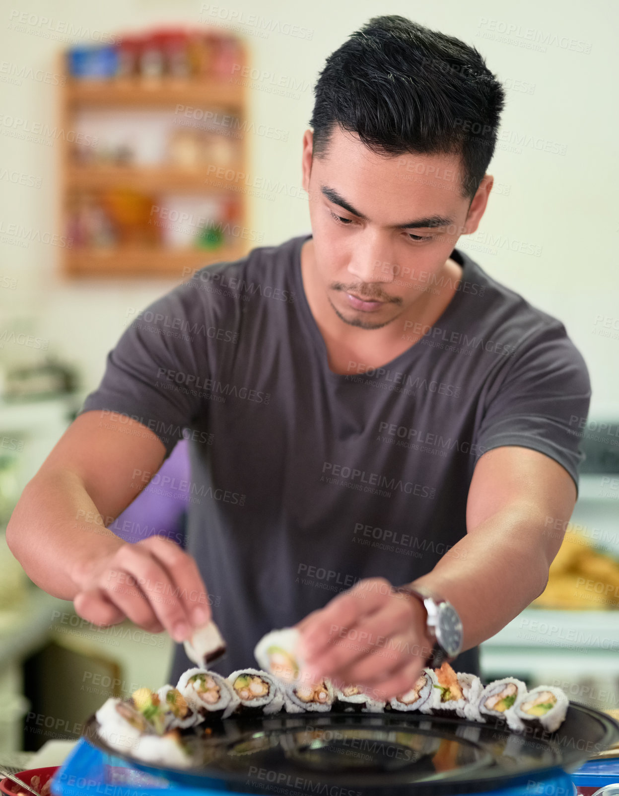 Buy stock photo Shot of a young man arranging sushi on a platter at home