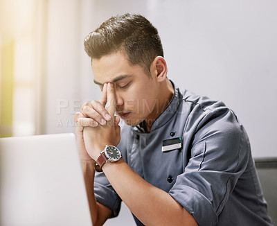 Buy stock photo Shot of a young man looking stressed while working on his laptop