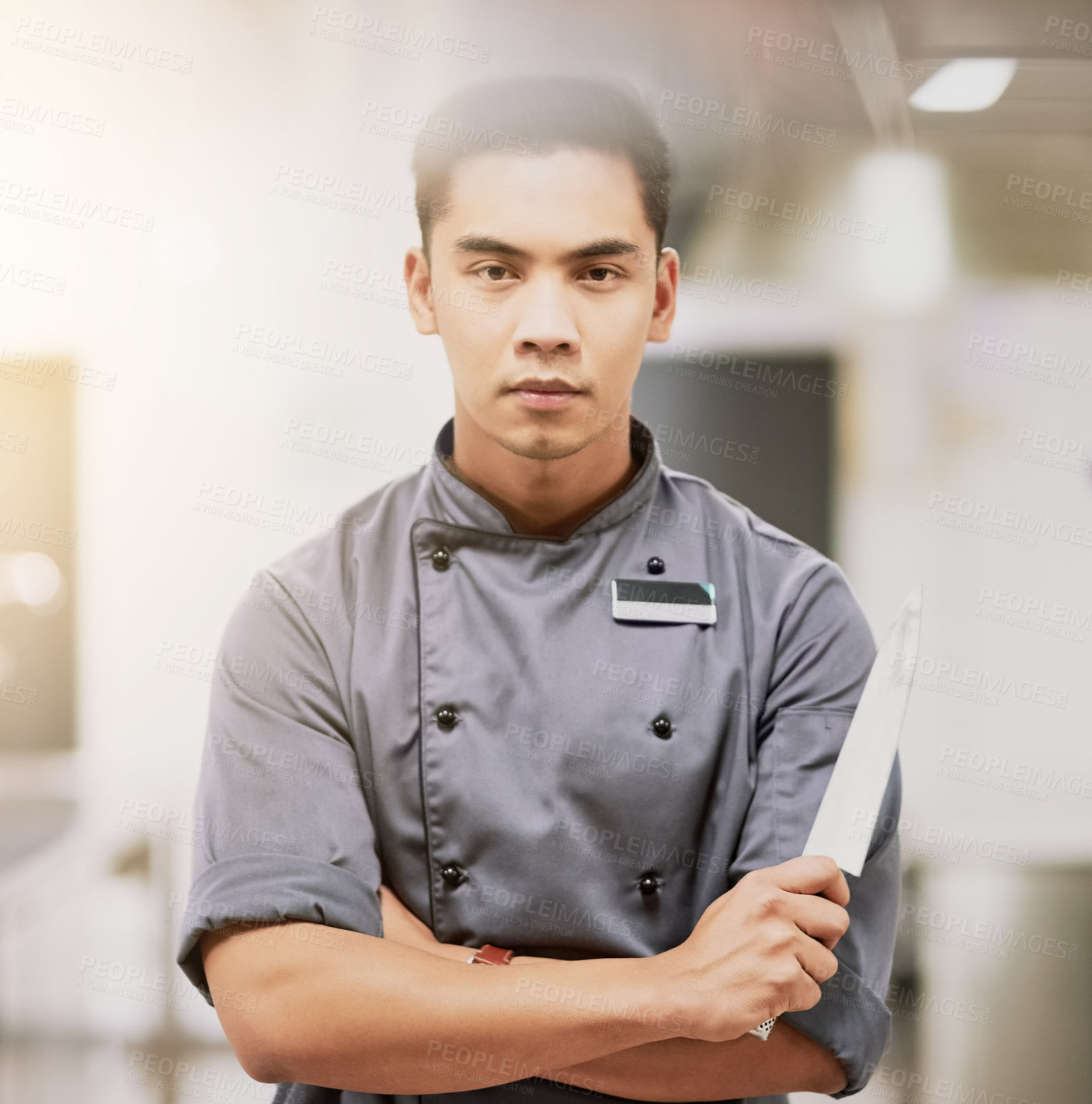 Buy stock photo Cropped portrait of a young male chef standing with a knife in his kitchen