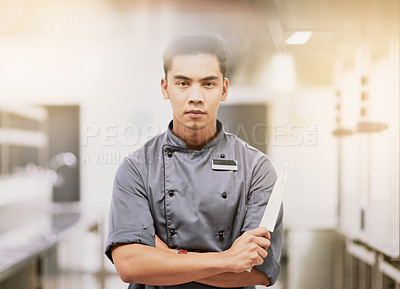 Buy stock photo Cropped portrait of a young male chef standing with a knife in his kitchen