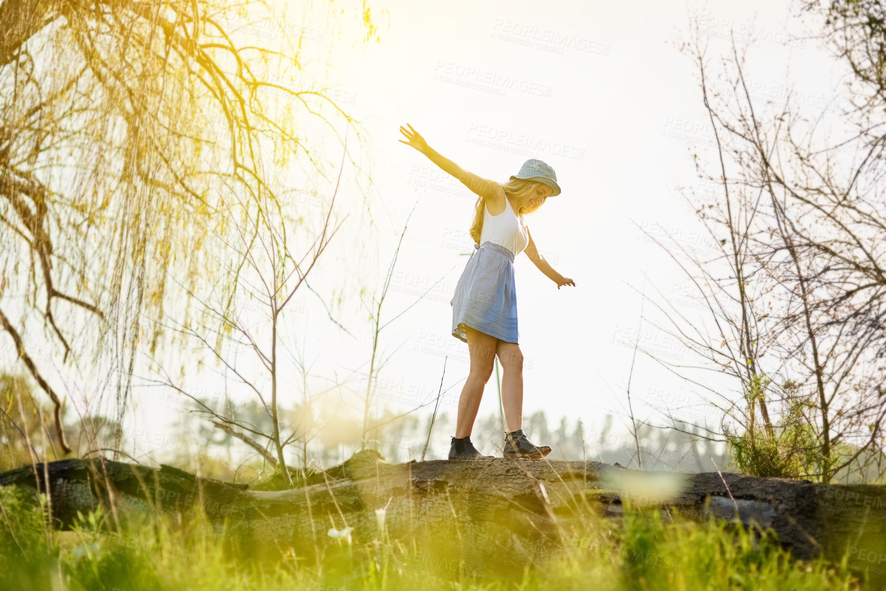 Buy stock photo Shot of a young woman on a tree stump out in the countryside