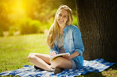 Buy stock photo Shot of a young student studying underneath a tree at the park
