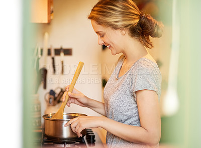 Buy stock photo Cropped shot of an attractive young woman cooking at home