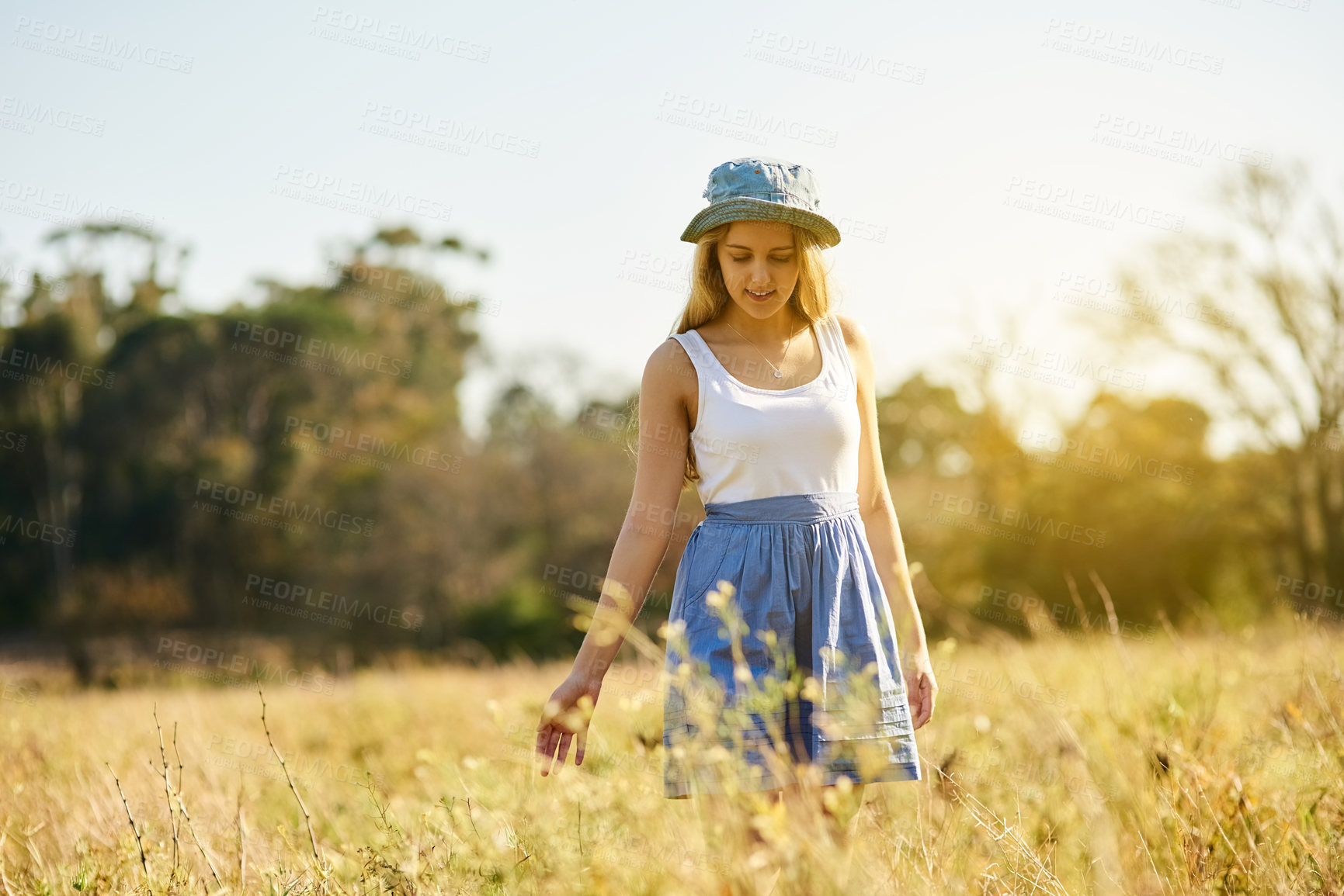 Buy stock photo Gen z, girl and walking in nature for freedom, travel and adventure in countryside for spring. Young woman, smile and sunshine in park or garden with flowers, leaves and outdoor journey in France