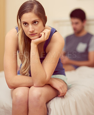 Buy stock photo Shot of an unhappy young woman sitting on the bed after having a fight with her boyfriend