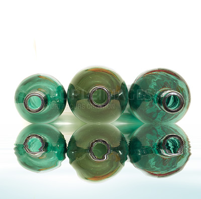 Buy stock photo Artistic still shot of colorful glass bottles with reflection, in the white isolated background. Three wine bottles are arranged in a leaner position in descending order with white background.