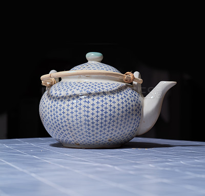 Buy stock photo A portrait image of a ceramic teapot with a black background. boiler kept on the table and with lighting effect from above. Vintage teapot design on it with the wooden handle, lead on it.  