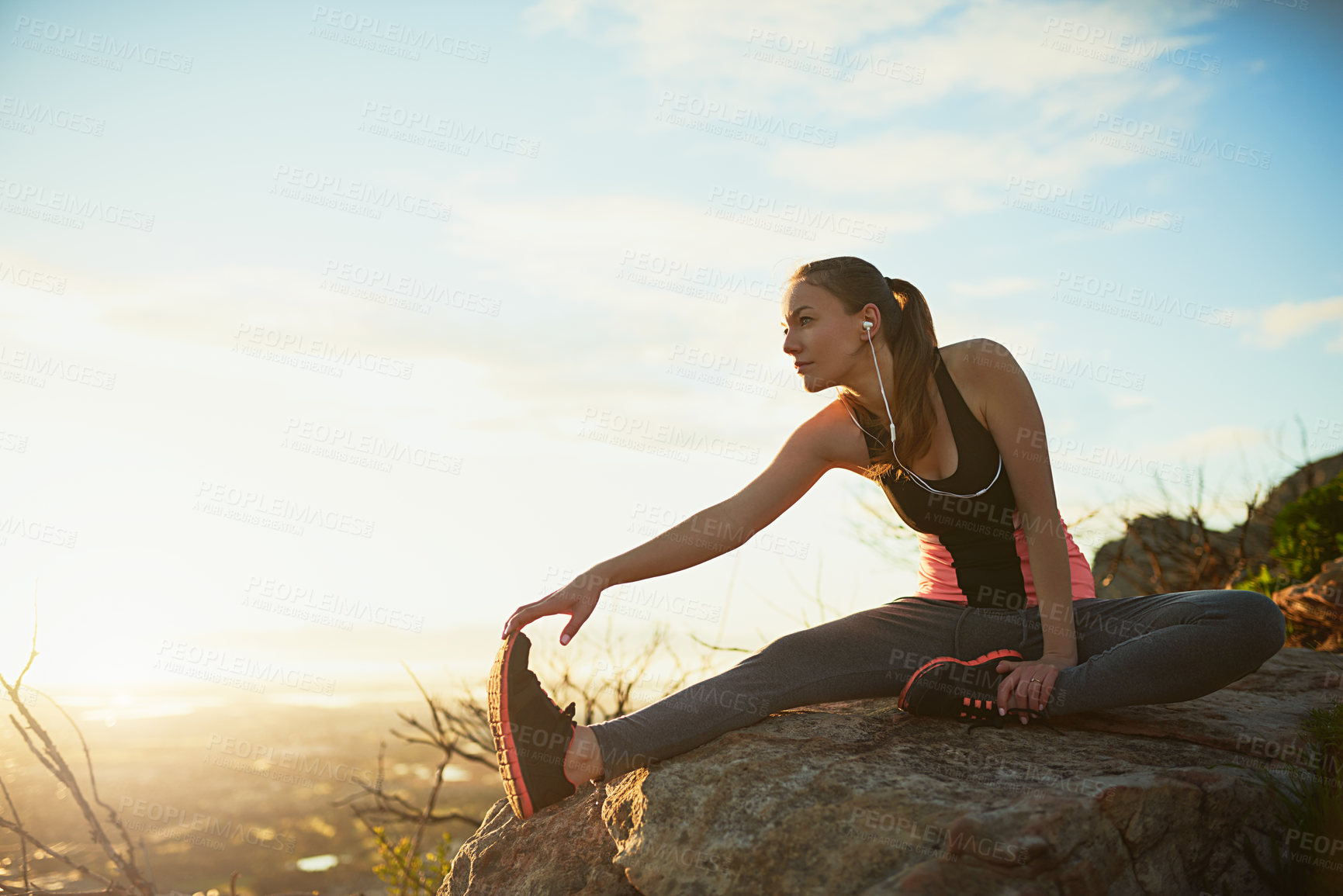 Buy stock photo Shot of a sporty young woman stretching outdoors