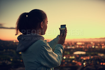 Buy stock photo Rearview shot of a young woman sending a text message while standing on a lookout point