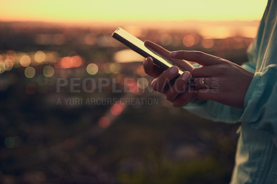Buy stock photo Shot of an unrecognizable woman sending a text message while standing on a lookout point