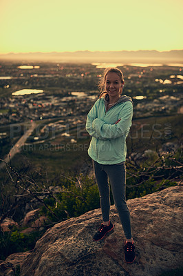 Buy stock photo Portrait of a sporty young woman standing with her arms crossed during a hike up the mountain