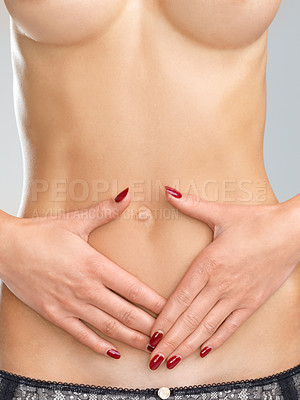 Buy stock photo Closeup image of a young womans hands over her flat bare stomach