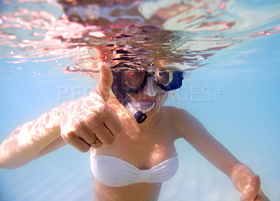 Buy stock photo Portrait of a young woman in snorkeling gear giving the thumb's up sign underwater