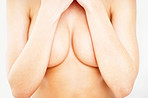 Mid section of a naked woman covering her breast