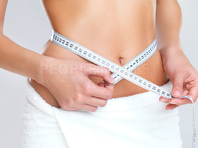 Buy stock photo Woman, hands and tape measure on stomach for lose weight, diet or slim body against a grey studio background. Hand of female person or model measuring waist in weightloss, results or healthy wellness