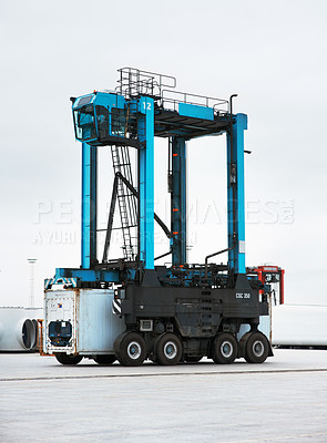 Buy stock photo A straddle carrier at the dockyard. A shipping industry vehicle. An empty straddle carrier standing at a port. The blue straddle truck is empty and is ready for loading and discharging operation.