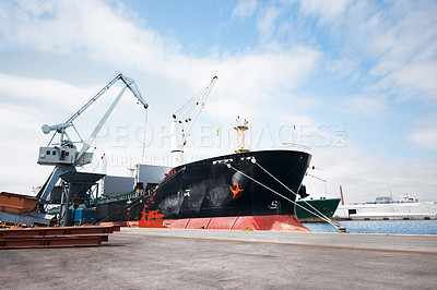 Buy stock photo A large ship at a harbour for shipping, freight and logistics against cloudy sky copy space background. Anchored ships in a port with copy space. Cargo bulk carrier being loaded for export sea trade 