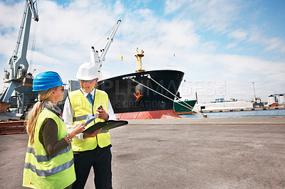Buy stock photo Two dock workers holding paperwork while standing in the shipyard