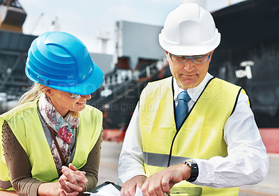 Buy stock photo Two dock workers holding paperwork while standing in the shipyard