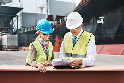 Buy stock photo Two dock workers holding paperwork while standing in the shipyard